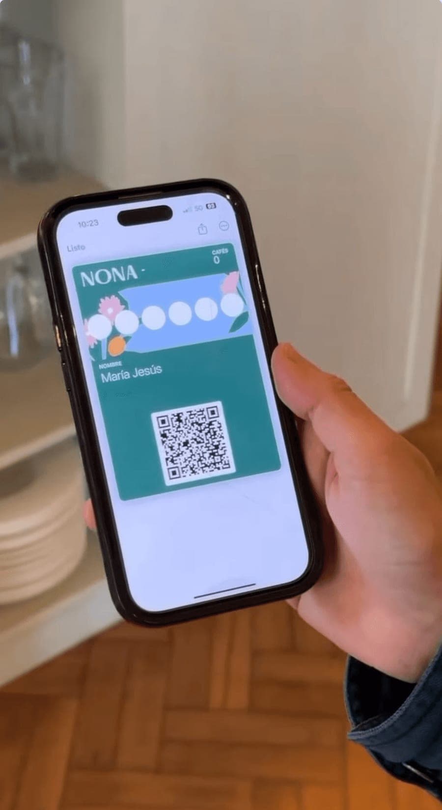 Una clienta sostiene su teléfono con la tarjeta de sellos de NONA abierta en la wallet.